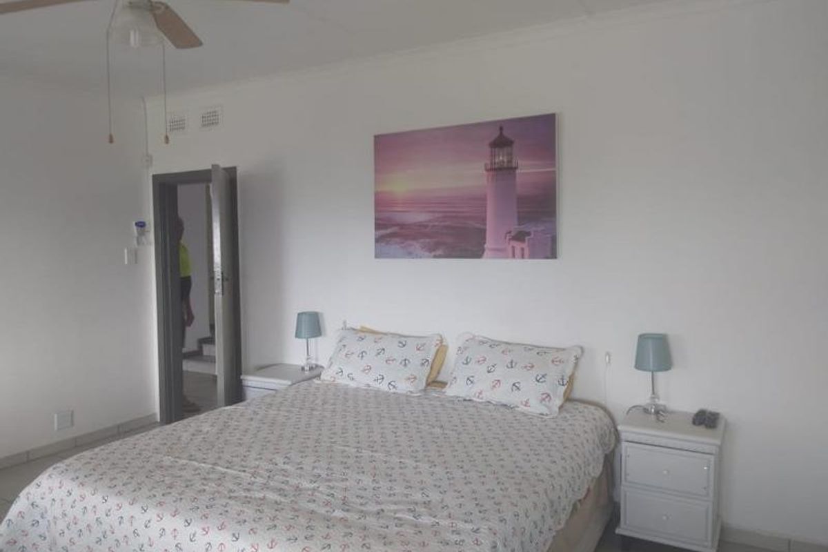 A simple bedroom featuring tiled flooring and a ceiling fan, providing a functional and neutral space.