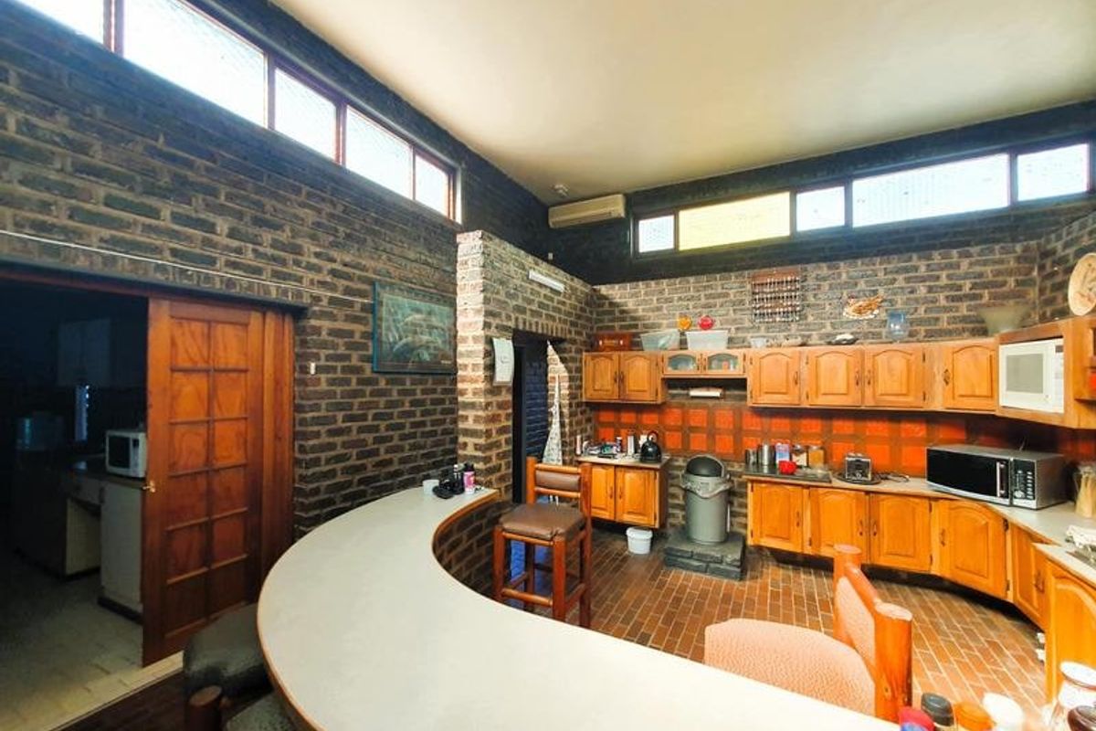 Spacious kitchen featuring exposed brick walls, wooden cabinetry, a curved breakfast bar, and unique clerestory windows providing natural light.
