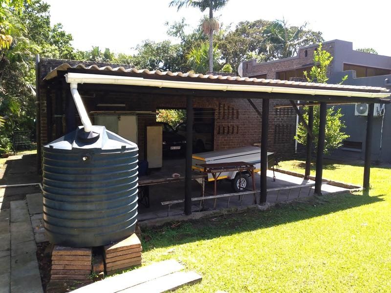 A functional outdoor carport area featuring exposed brick walls, a covered roof structure, and an integrated water storage tank system.