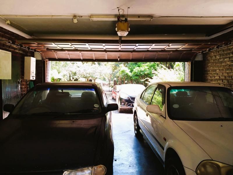 A functional garage space featuring exposed brick walls, a sectional overhead door, and an automated garage door motor.