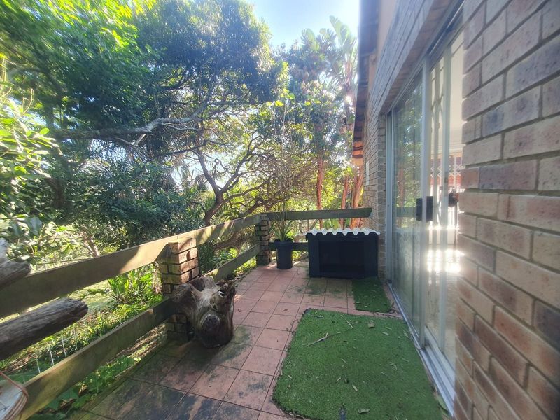 A private balcony featuring tiled flooring, a brick facade, and a timber balustrade, offering a peaceful outdoor space with garden views.