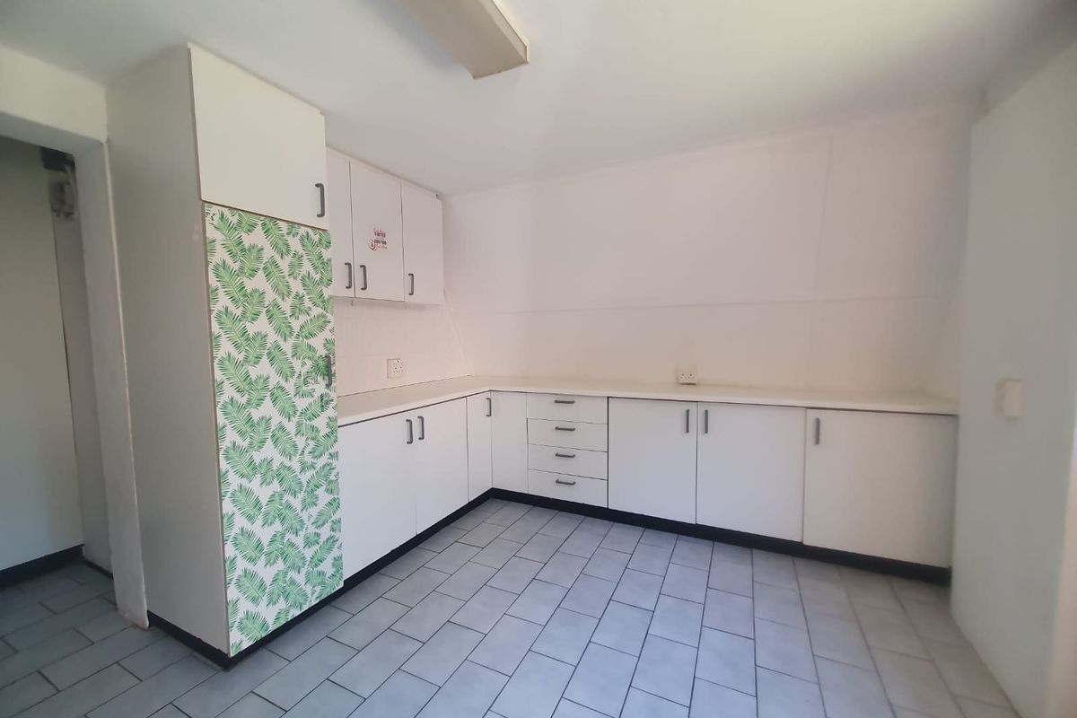 A functional, empty kitchen featuring white laminate cabinetry, ample counter space, and tiled flooring, offering a blank canvas for modern renovation.