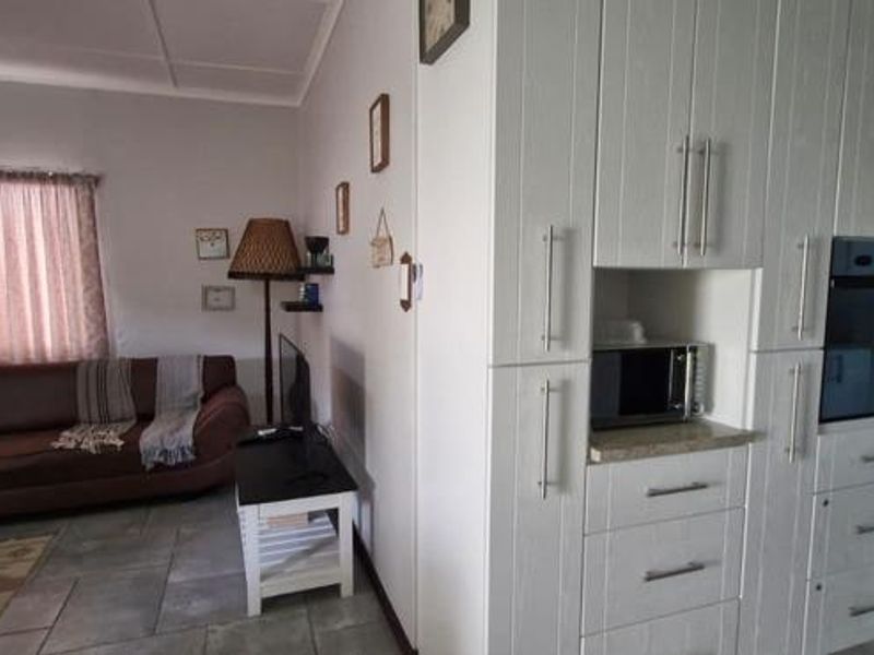 Open plan living area featuring tiled flooring and a modern white built-in kitchen cabinetry unit with integrated oven.