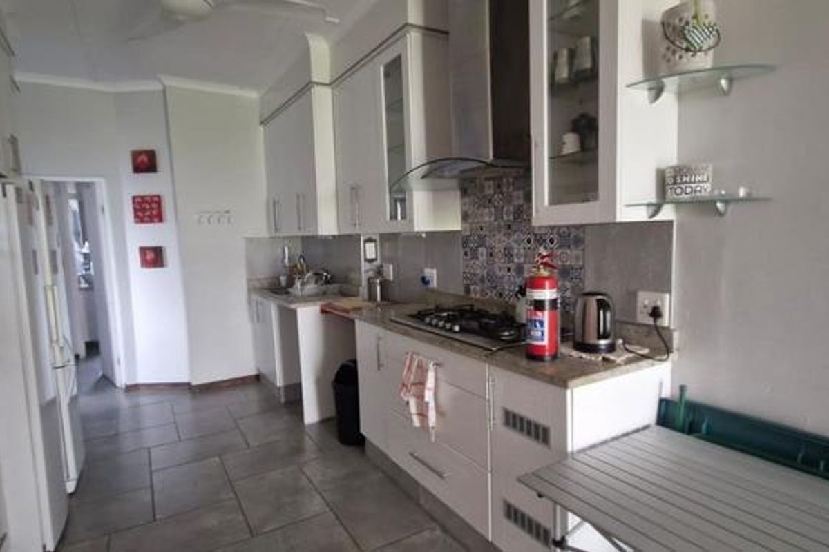 A functional kitchen featuring white cabinetry, stone countertops, a gas hob, built-in oven, and tiled flooring with a decorative backsplash.