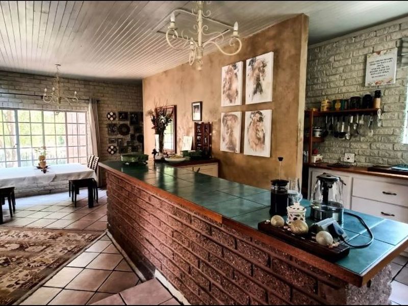 Open-plan living and kitchen area featuring exposed brick walls, a tiled island bench, and timber ceiling finishes in a rustic, lived-in style.