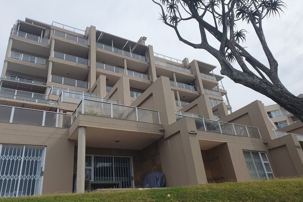 A low-angle view of a multi-story apartment building featuring tiered balconies with glass balustrades and secure ground-floor access.