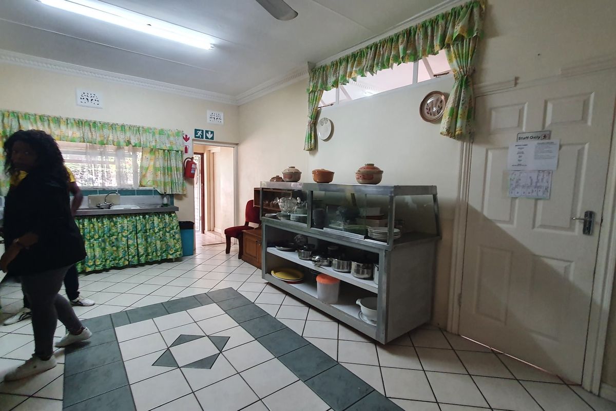 A functional kitchen area featuring tiled flooring, a stainless steel sink, and basic cabinetry, suitable for renovation to modernize the space.