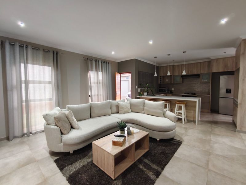 Spacious open-plan living area featuring a modern kitchen with island, tiled flooring, and recessed lighting, creating a seamless flow for contemporary living.