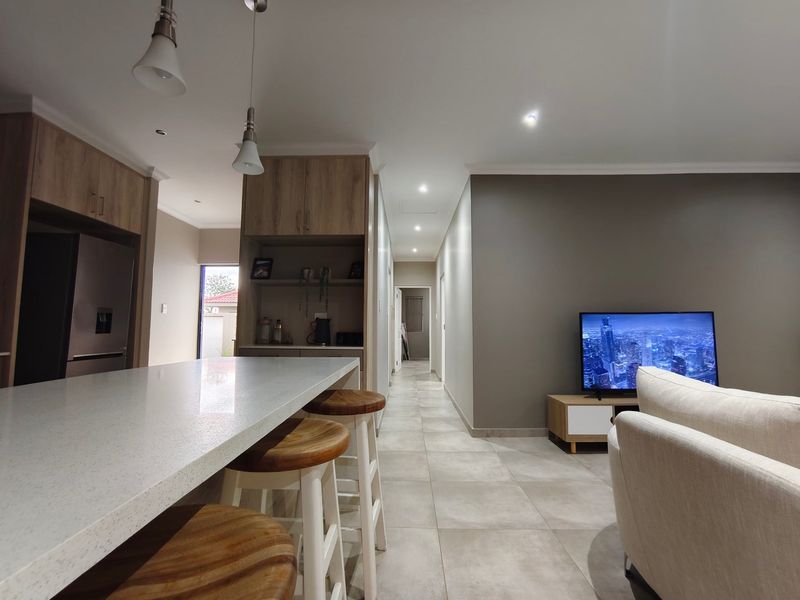 Modern open-plan living area featuring a spacious kitchen island with quartz countertops, sleek cabinetry, and neutral tiled flooring throughout.