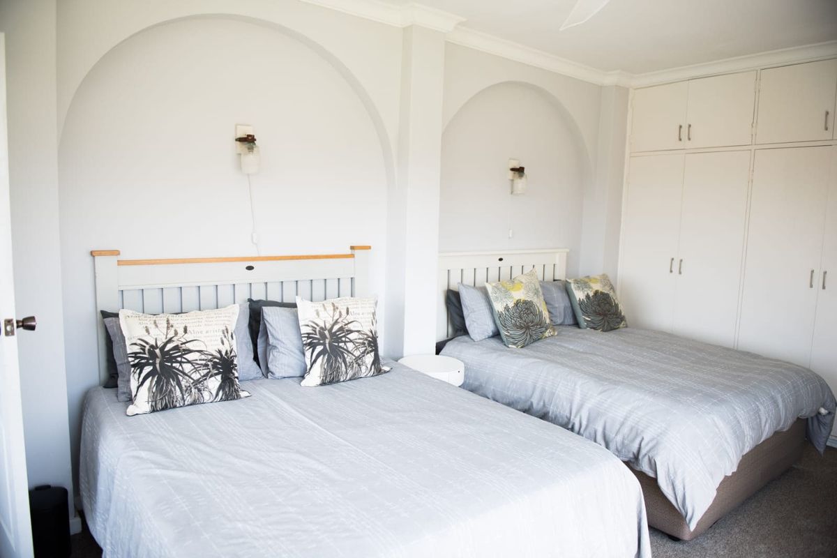 A spacious bedroom featuring built-in cupboards, arched wall recesses with integrated lighting, and a ceiling fan.