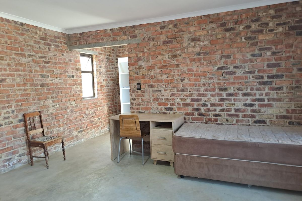 A bedroom featuring rustic exposed brick walls and polished concrete flooring, offering a unique industrial aesthetic.