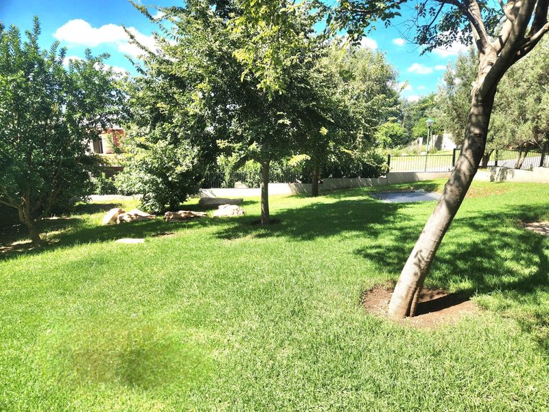 A well-maintained garden area featuring a lush green lawn, mature trees, and perimeter fencing, providing a private and serene outdoor space.