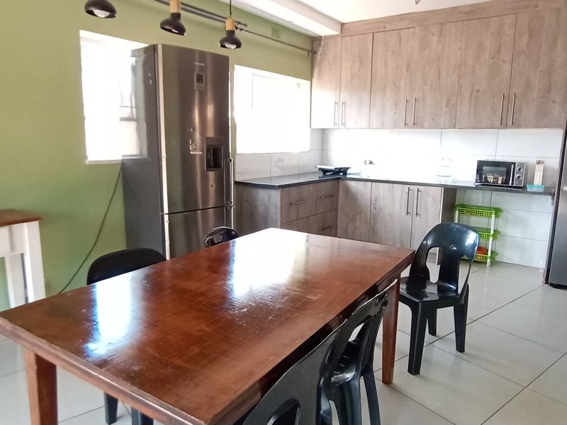 A functional kitchen featuring wood-look cabinetry, tiled flooring, and integrated appliances, offering a practical layout for daily meal preparation.
