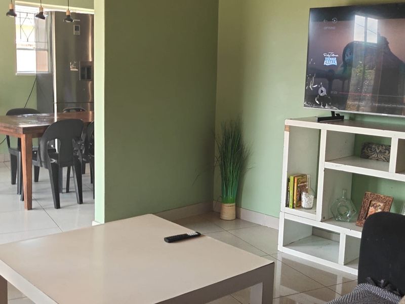 An open-plan living and dining area featuring light-colored tiled flooring and neutral wall finishes, providing a functional and connected living space.