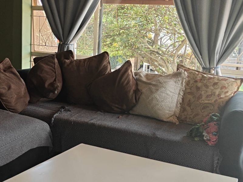 A living room area featuring a large window with security bars, providing natural light and a view of the outdoor space.