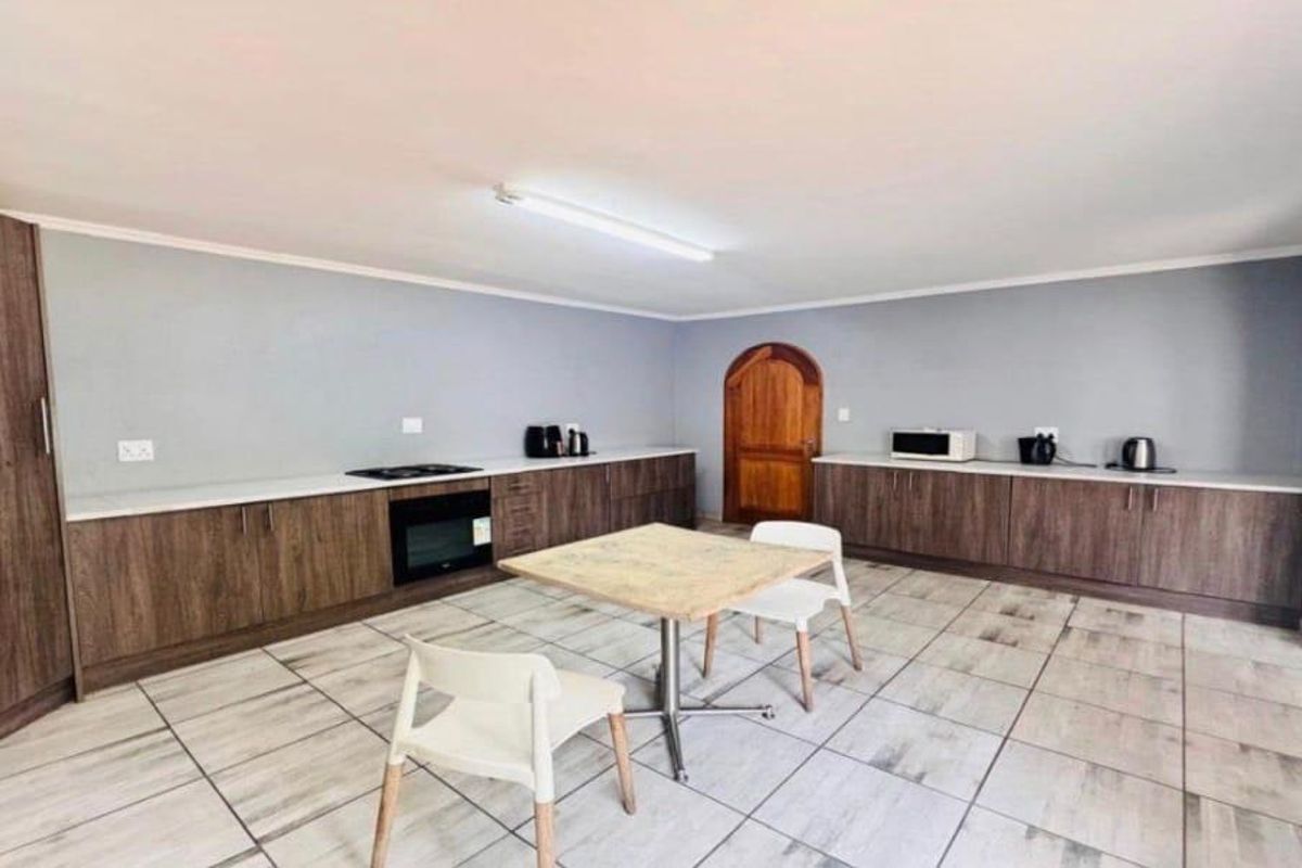 A spacious kitchen featuring extensive wood-finish cabinetry, light countertops, built-in oven and hob, and neutral tiled flooring.