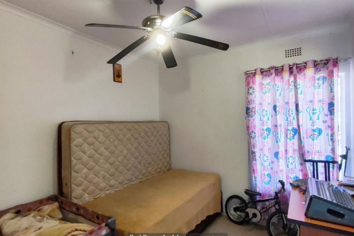 A standard bedroom featuring a ceiling fan and a ventilation grille, providing a functional space for rest.