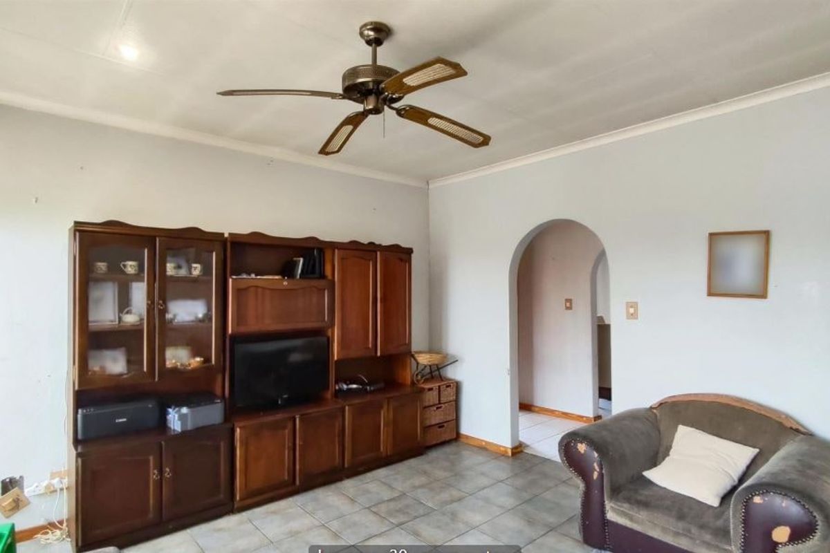 A living room featuring tiled flooring, a ceiling fan, and an arched doorway leading to an adjacent space.