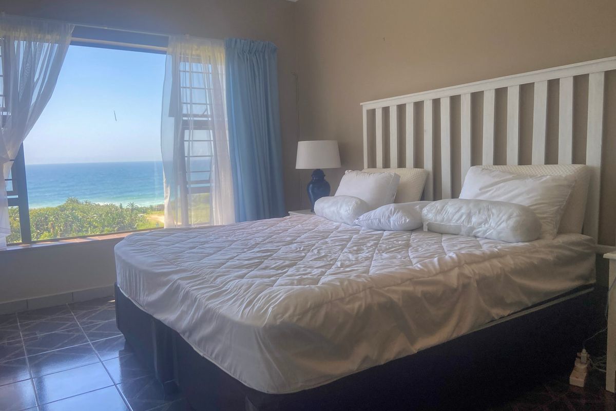 A bedroom featuring tiled flooring and a large window offering expansive ocean views.