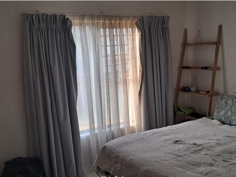 A bedroom featuring a built-in wardrobe and window with curtain tracks, providing a functional space with natural light.