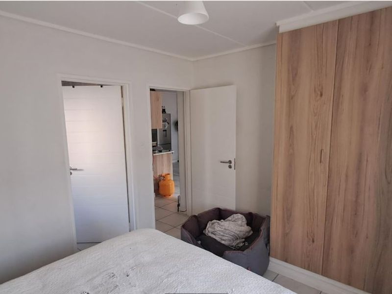 A bedroom featuring built-in wooden wardrobes and access to an adjacent room.