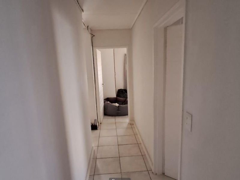 A simple, neutral hallway featuring tiled flooring and access to adjacent rooms.