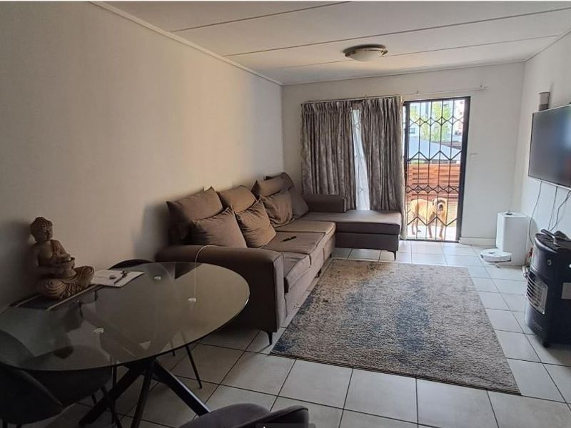 A functional living room featuring tiled flooring, a security gate, and access to an outdoor area, providing a comfortable and practical living space.