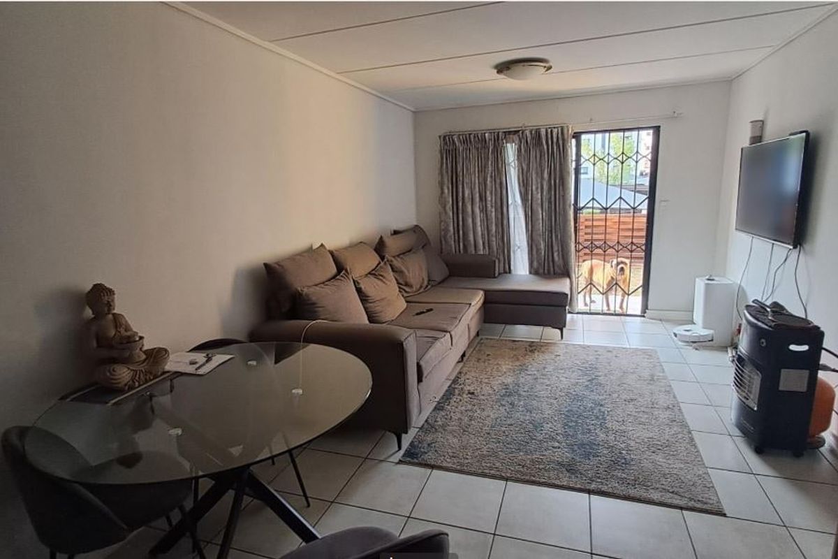 A functional living room featuring tiled flooring, a security gate, and access to an outdoor area, providing a comfortable and practical living space.