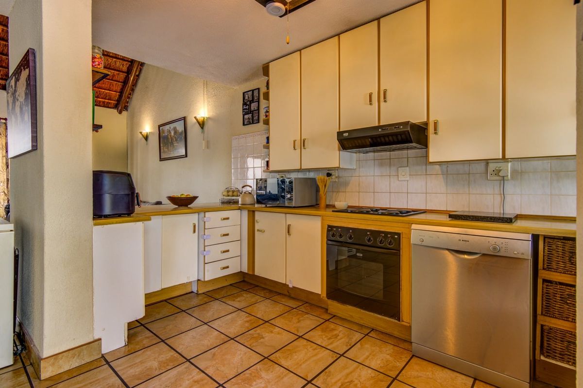 A functional kitchen featuring built-in cabinetry, a fitted oven, hob, extractor fan, and tiled flooring, offering a practical layout for daily meal preparation.