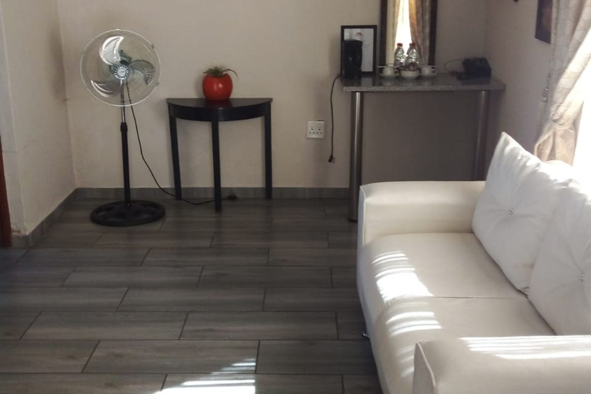 A living room area featuring wood-look tile flooring and neutral wall finishes, providing a functional space for relaxation.