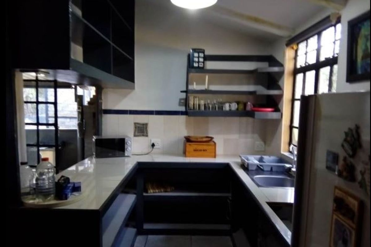 A functional kitchen featuring u-shaped cabinetry, open shelving, a tiled backsplash, and a stainless steel sink with natural light from a window.