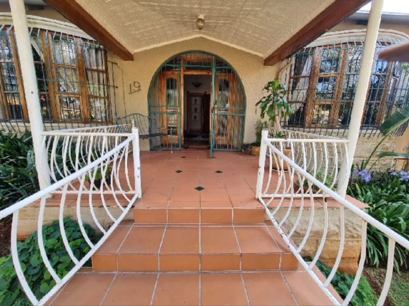 Front entrance featuring tiled steps, a covered porch area, and secure wrought iron gate and window bars.