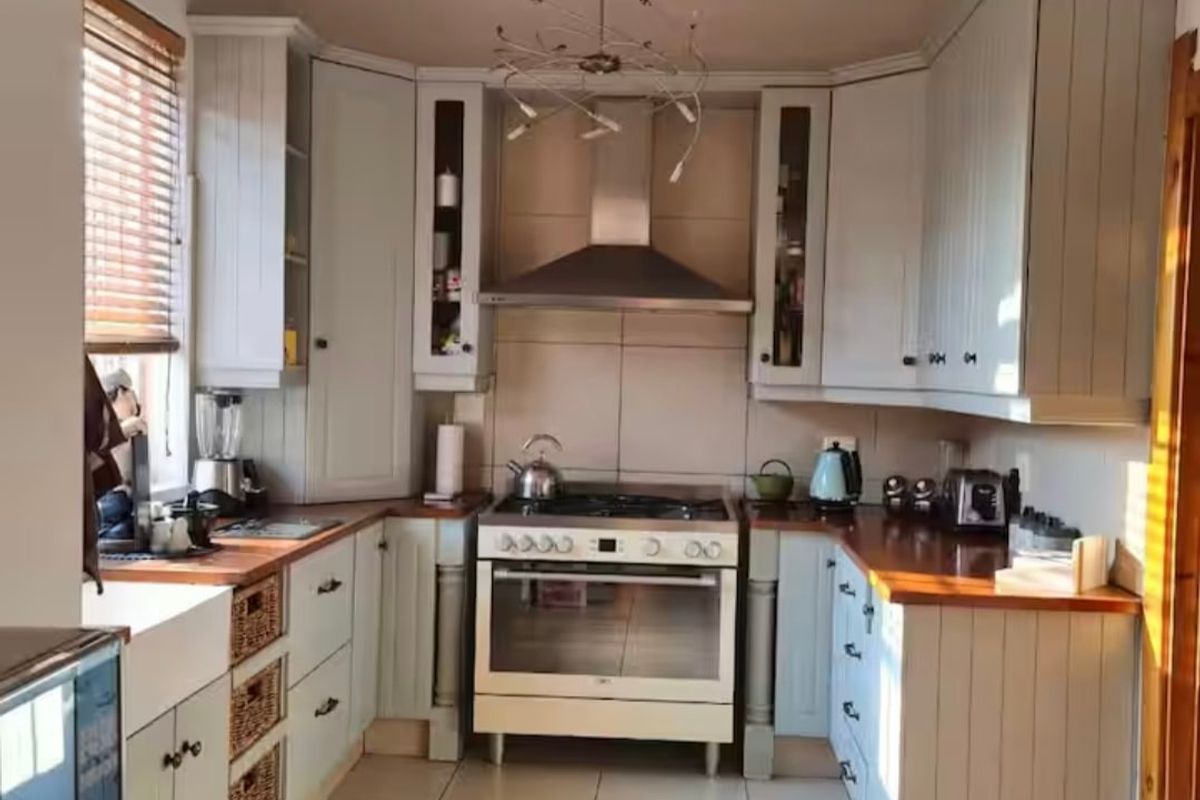 A well-appointed kitchen featuring timber countertops, a farmhouse sink, gas stove with extractor, and elegant coffered ceiling detailing.
