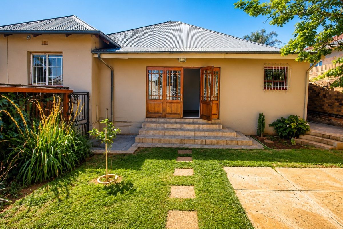 Rear view of the house featuring a corrugated metal roof, tiled entrance steps, and timber-framed double doors leading into the home.
