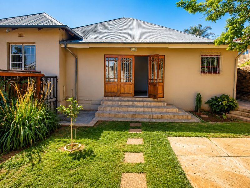 Rear view of the house featuring a corrugated metal roof, tiled entrance steps, and timber-framed double doors leading into the home.