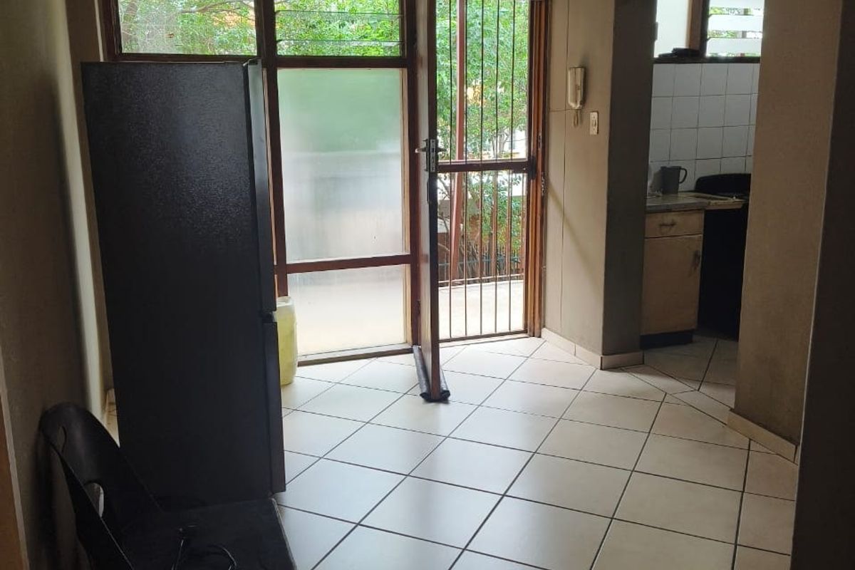 A functional kitchen area featuring tiled flooring, built-in cabinetry, and a security gate leading to an outdoor space.