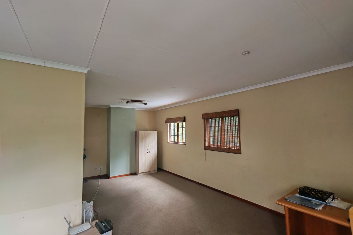 A spacious, neutral-toned bedroom featuring carpeted flooring, recessed ceiling lighting, and timber-framed windows, offering a blank canvas for personalization.