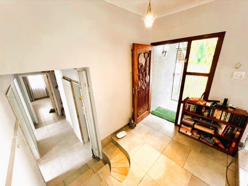 Entrance foyer featuring tiled flooring, a decorative carved wooden front door, and a stained glass side panel, leading into the interior living spaces.