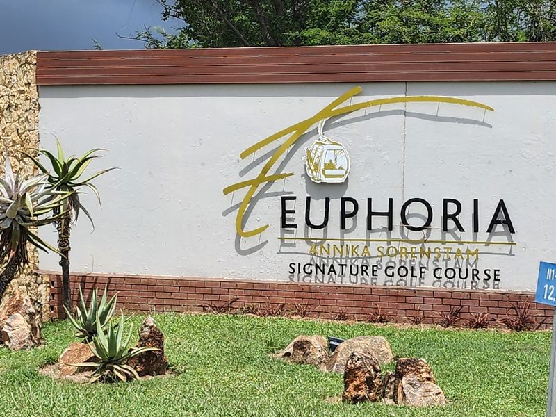 Entrance signage for Euphoria Golf Estate, featuring a stone and brick wall with landscaped garden surroundings.