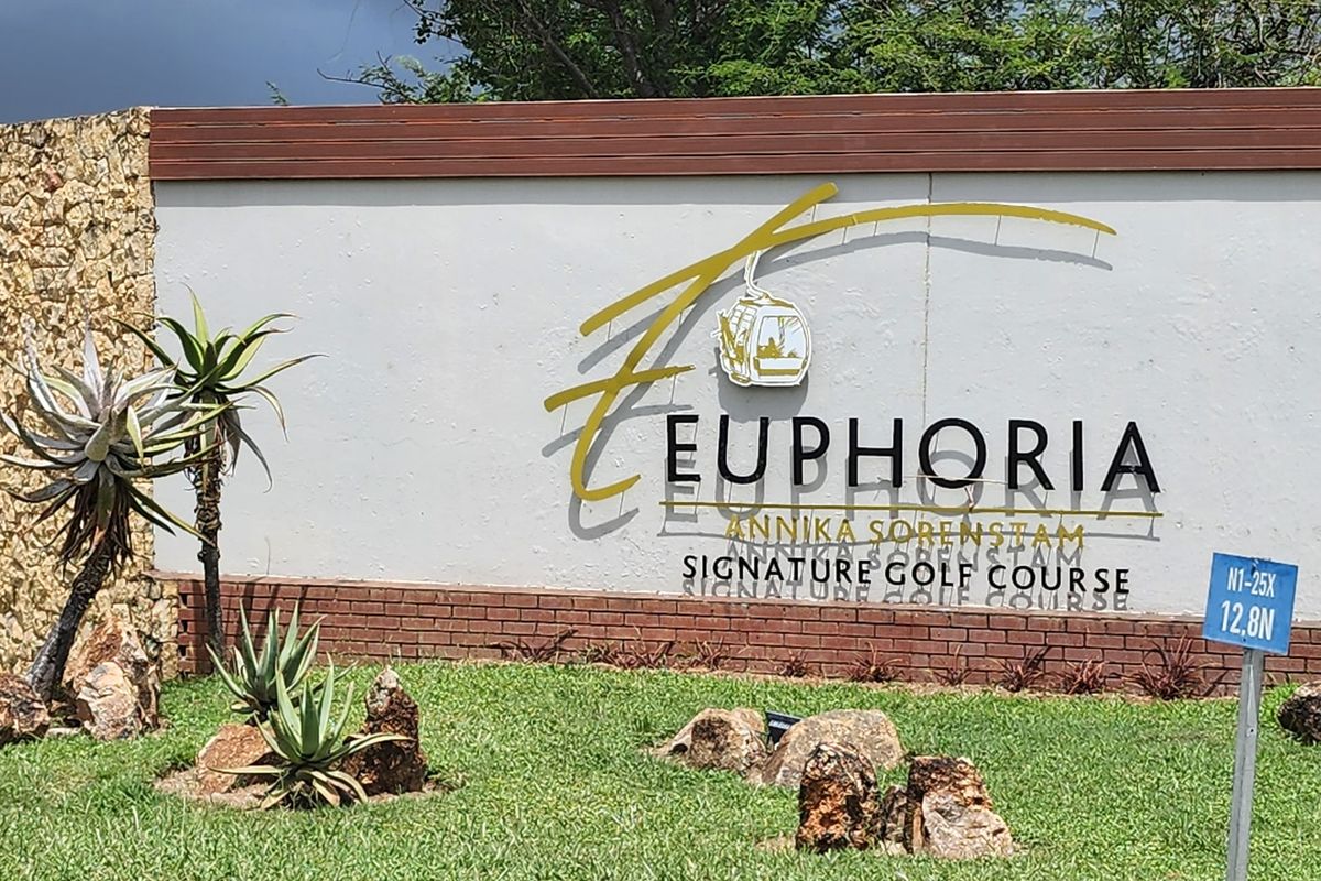 Entrance signage for Euphoria Golf Estate, featuring a stone and brick wall with landscaped garden surroundings.