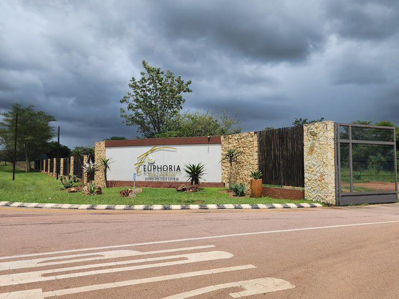 Entrance view of Euphoria estate featuring stone-clad boundary walls, security gate, and professional signage.