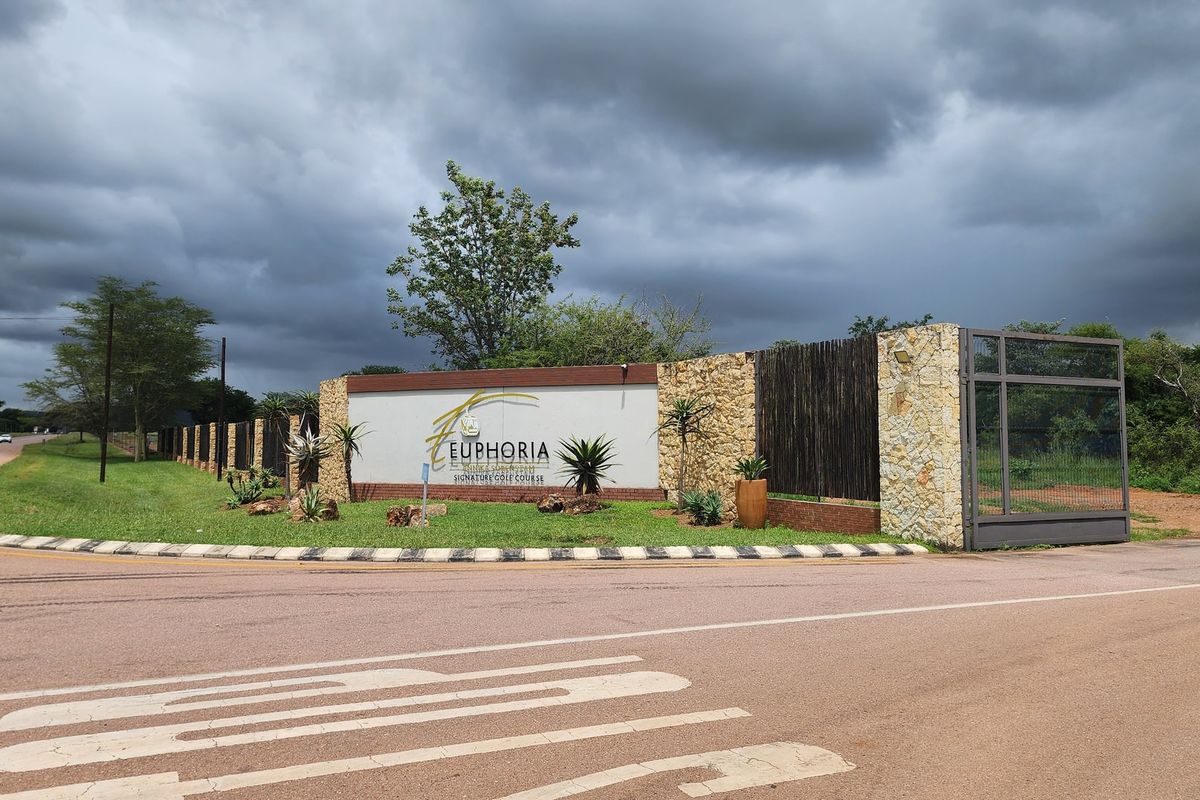 Entrance view of Euphoria estate featuring stone-clad boundary walls, security gate, and professional signage.