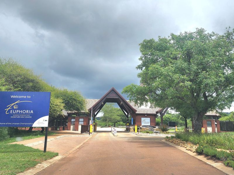 The entrance to Euphoria Golf Estate featuring a paved driveway, security gatehouse, and boom gate access control.