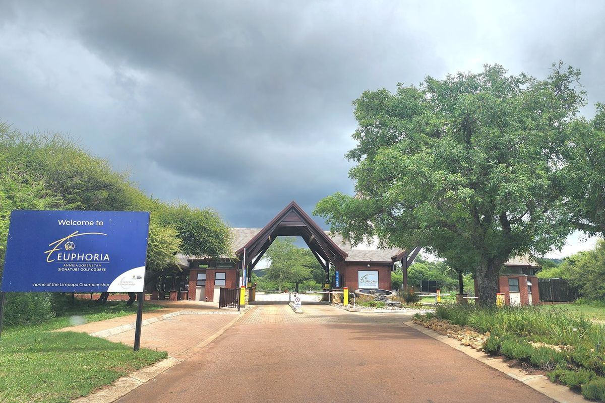 The entrance to Euphoria Golf Estate featuring a paved driveway, security gatehouse, and boom gate access control.