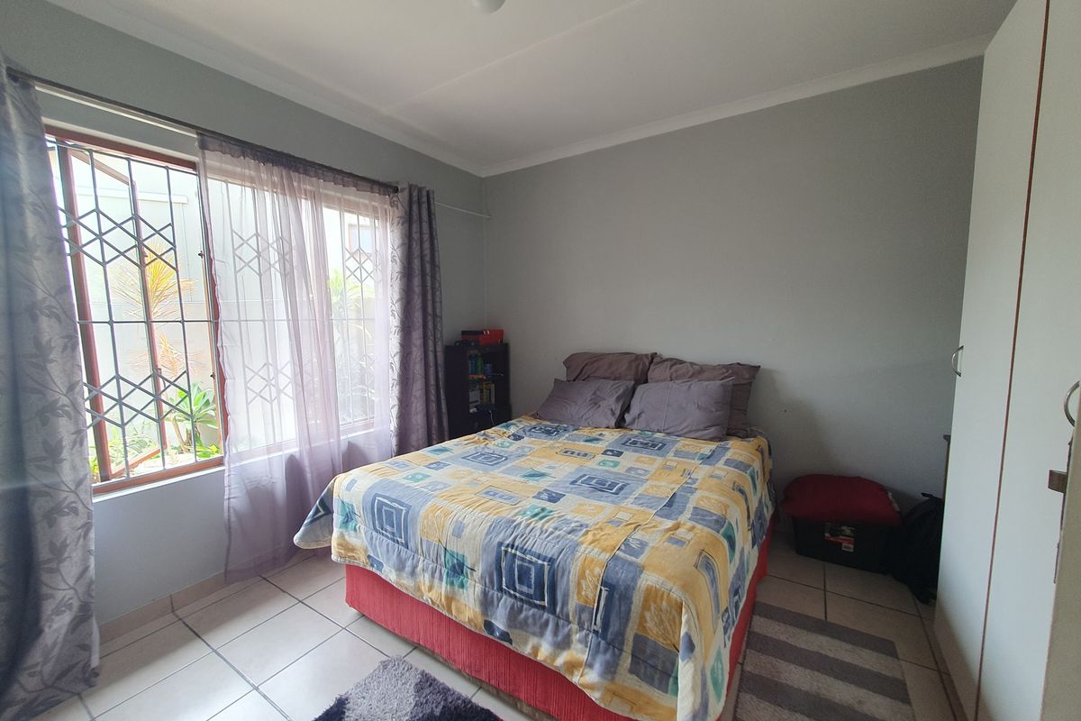 A functional bedroom featuring tiled flooring, a built-in wardrobe, and a window fitted with a security gate for added peace of mind.