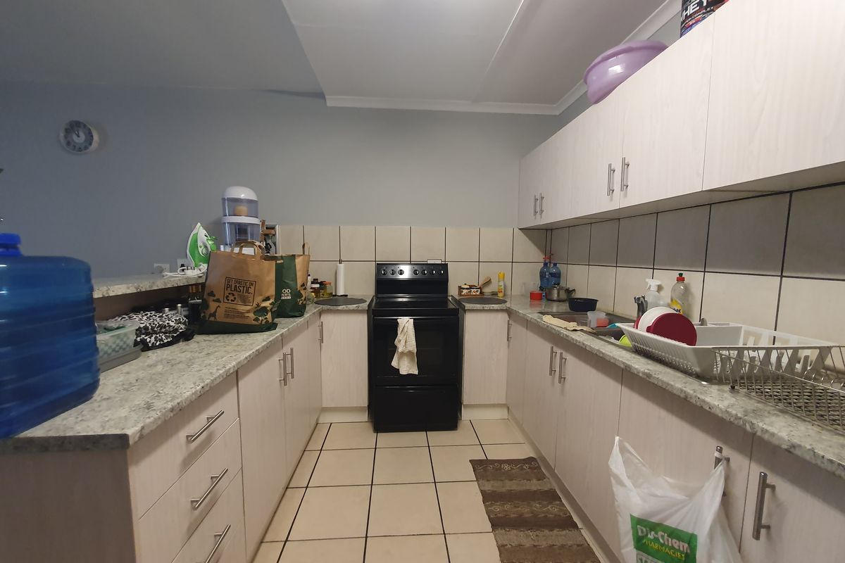 A functional kitchen featuring light-toned cabinetry, granite-look laminate countertops, ceramic tile backsplash, and a freestanding electric stove.