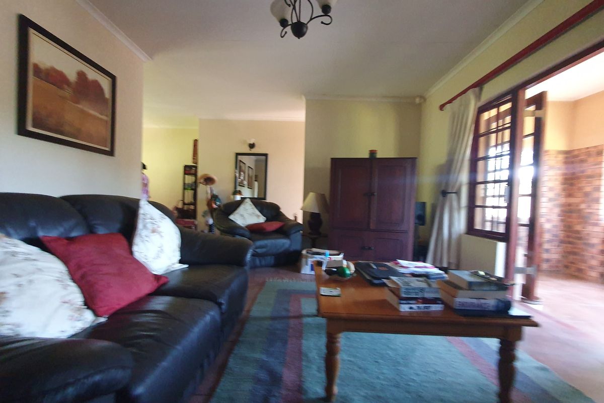 A living room area featuring coving, a timber-framed glass door leading to an outdoor space, and a central ceiling light fixture.