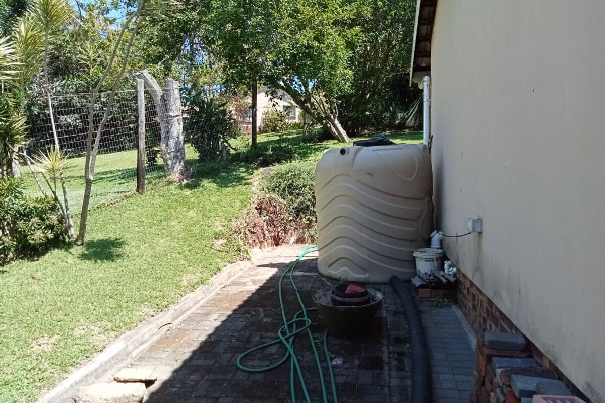 Rear exterior area featuring a water storage tank, paved walkway, and access to the garden space.