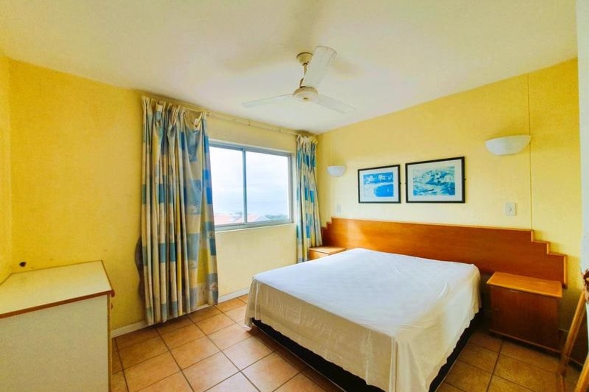 A bedroom featuring tiled flooring, a ceiling fan, and a built-in headboard with integrated bedside storage.