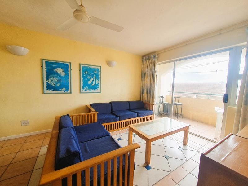A living room featuring tiled flooring, a ceiling fan, and sliding glass doors that open onto a balcony.